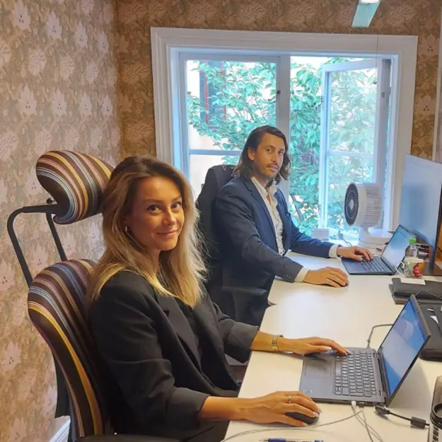 två dynamicskonsulter som jobbar med varsin laptop framför ett fönster